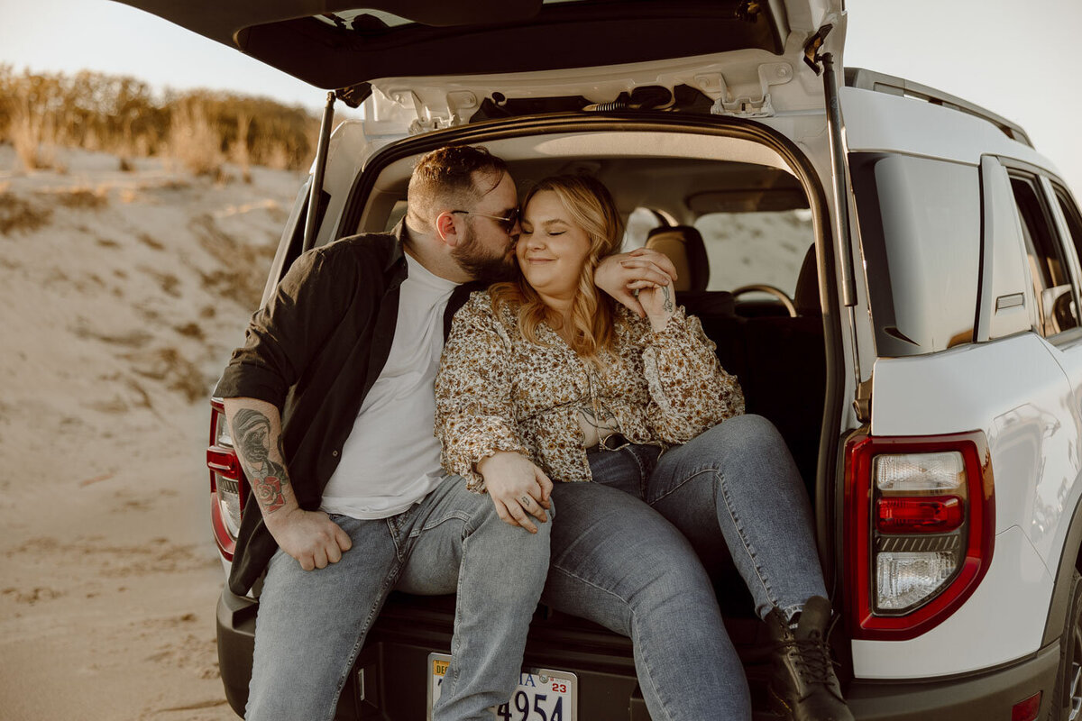 Couple sits in the back of their car enjoying the sunset