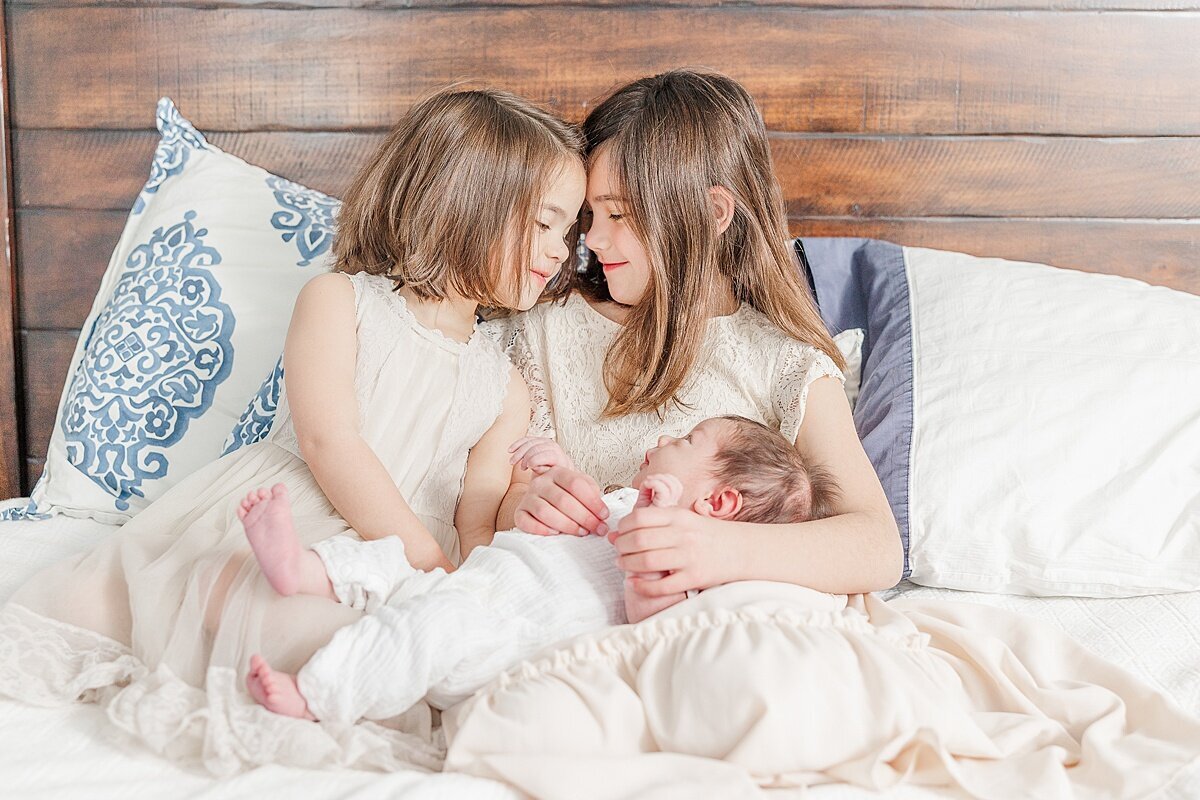 siblings on bed dung in-home newborn photo session with Sara Sniderman Photography in Needham Massachusetts