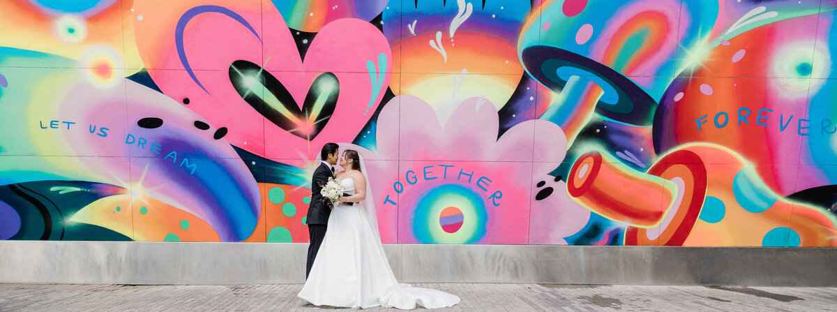 Newlyweds stand outside a NYC mural
