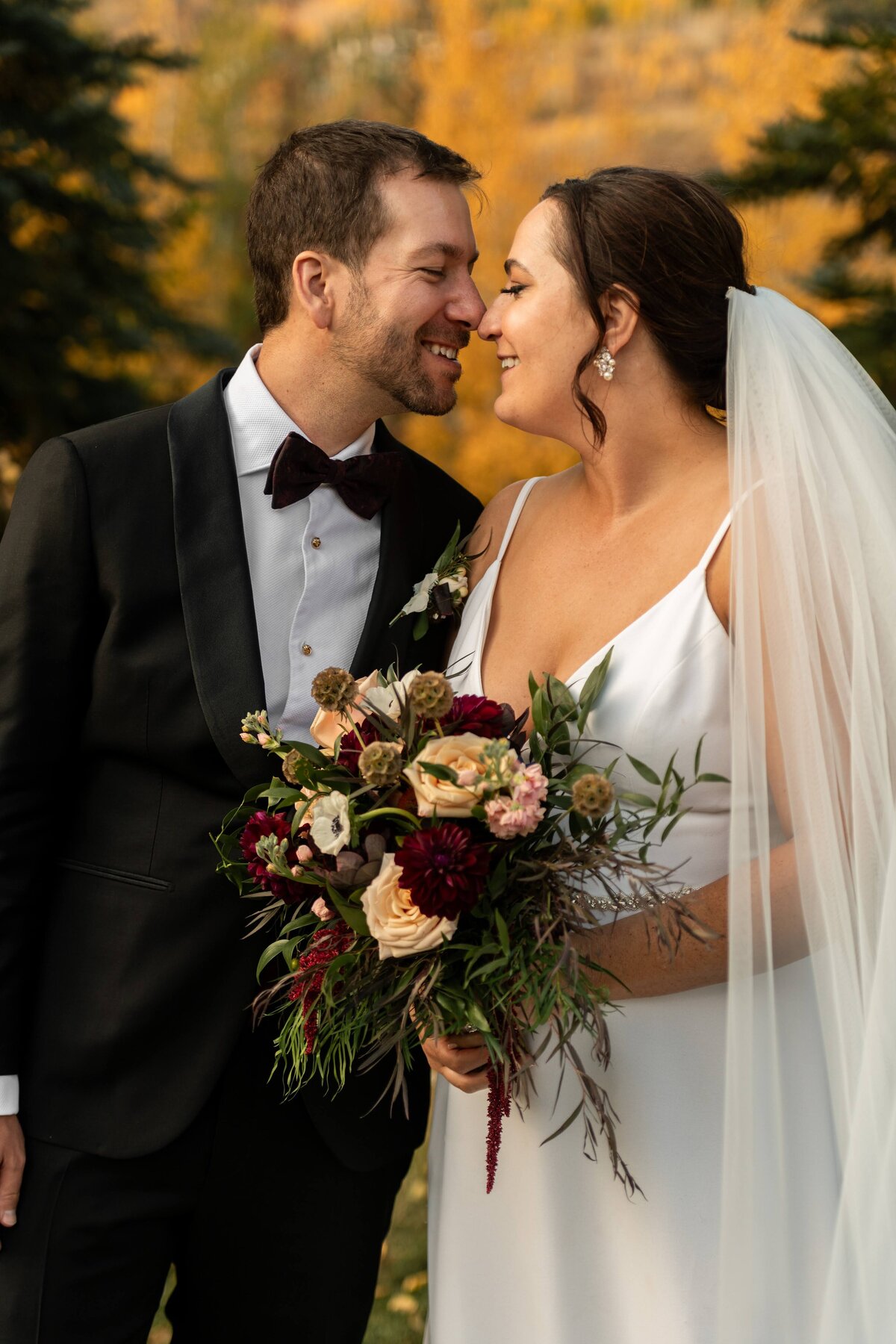 Bride and groom with burgundy and peach bouquet.