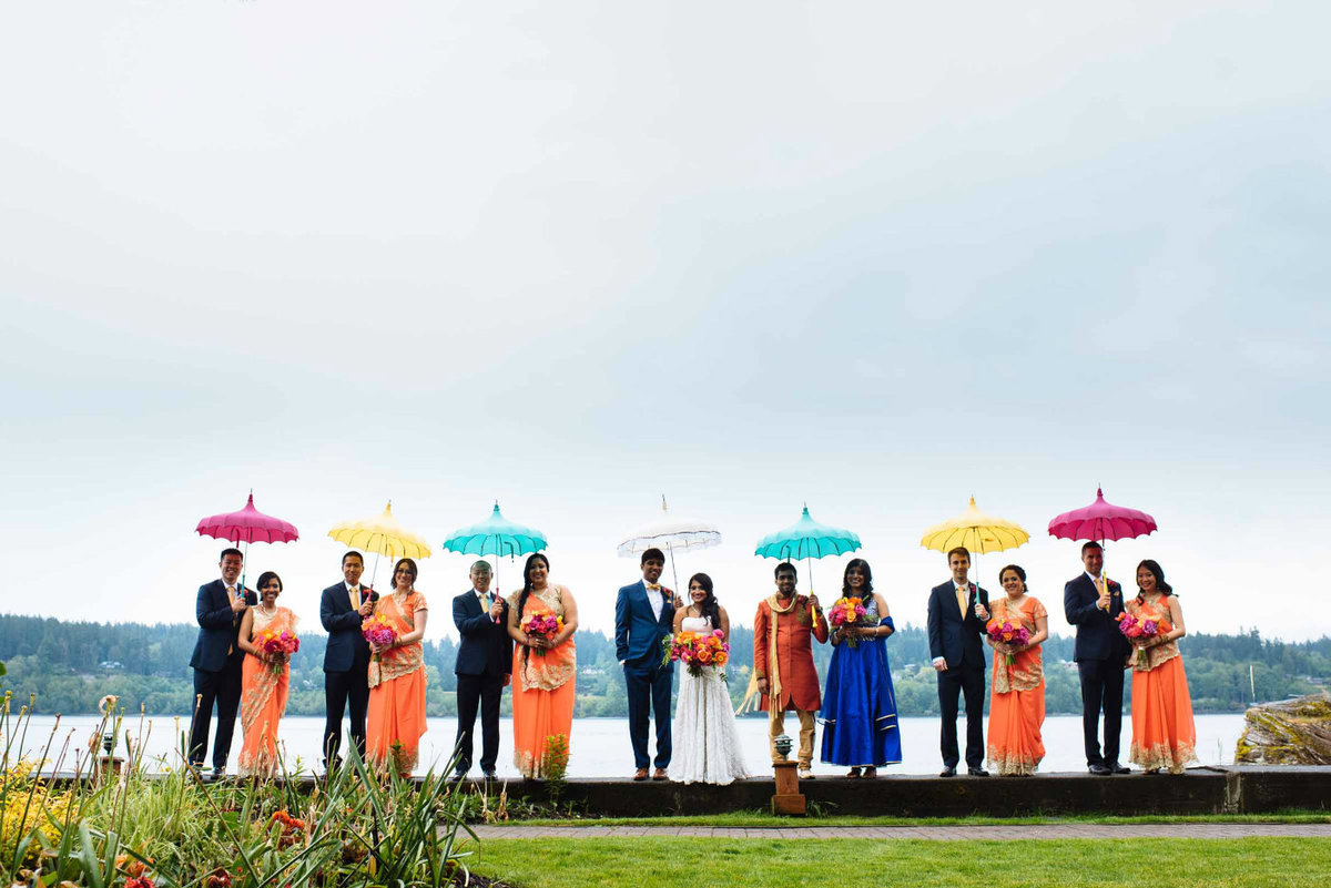 Wedding party holding bright umbrellas bring cheer to the gloomy spring day.