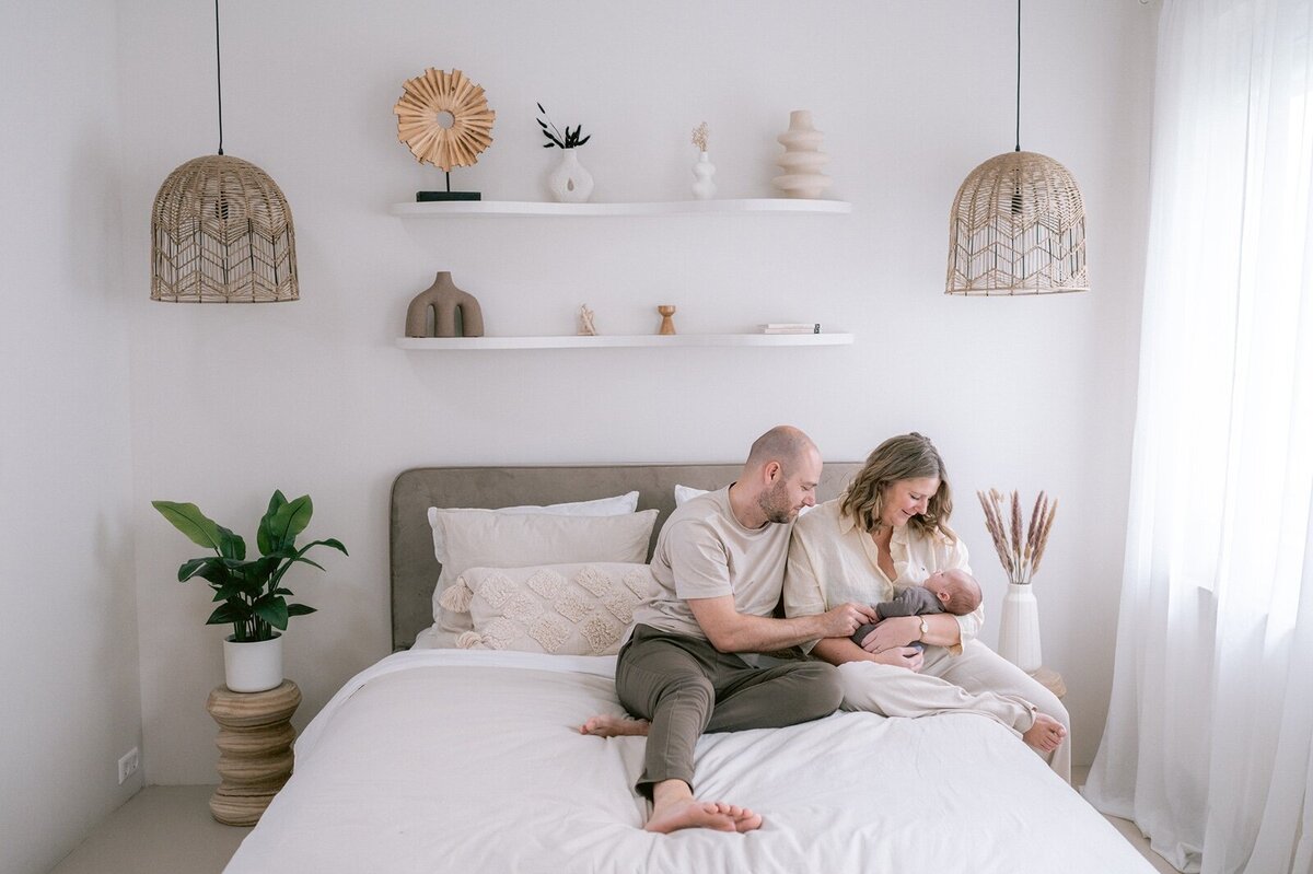 Vader en moeder op bed met newborn baby