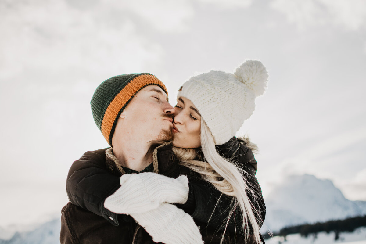 jackson hole photographers photographs woman on her fiances back leaning forward to kiss him during their Grand Teton winter engagement session