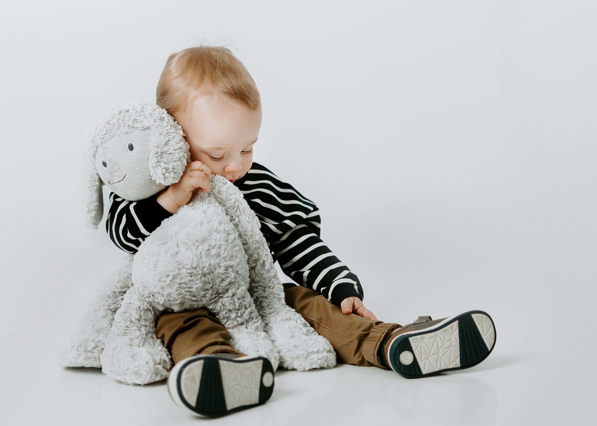 Capture precious moments with a baby and stuffed animal on a white background taken by a Pittsburgh family photographer.