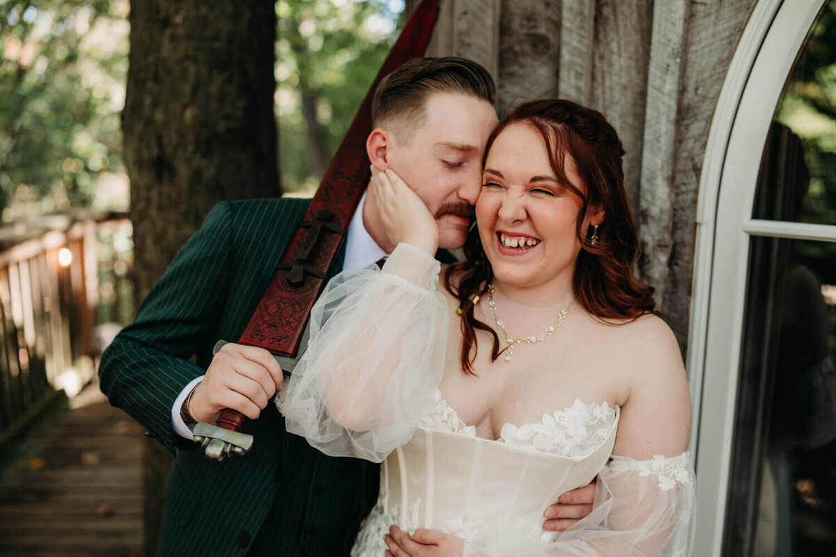 Couple laughs as they stand next to treehouse