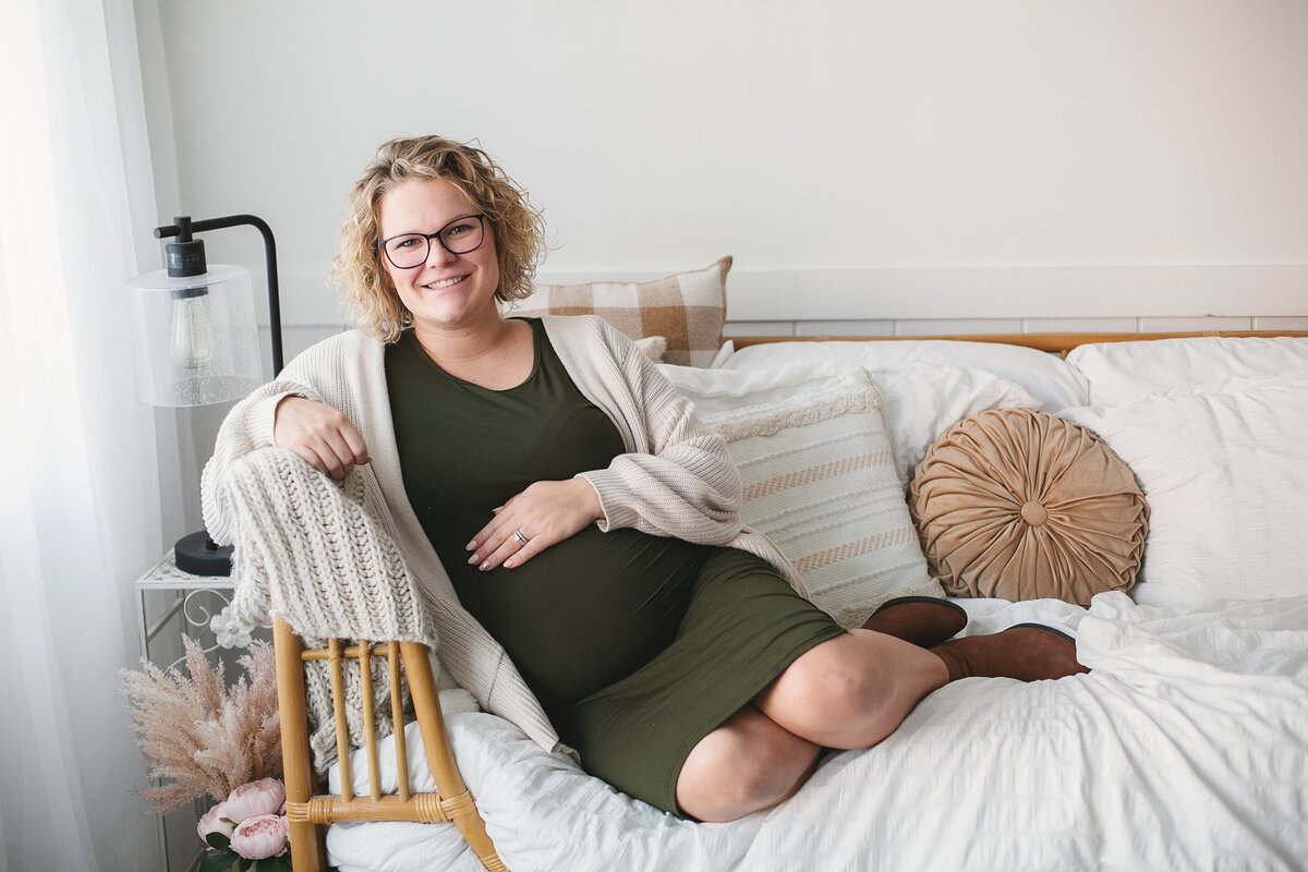 glowing-pregnant-woman-in-cozy-indoor-setting-smiling-on-bed-during-maternity-photoshoot-in-indianapolis