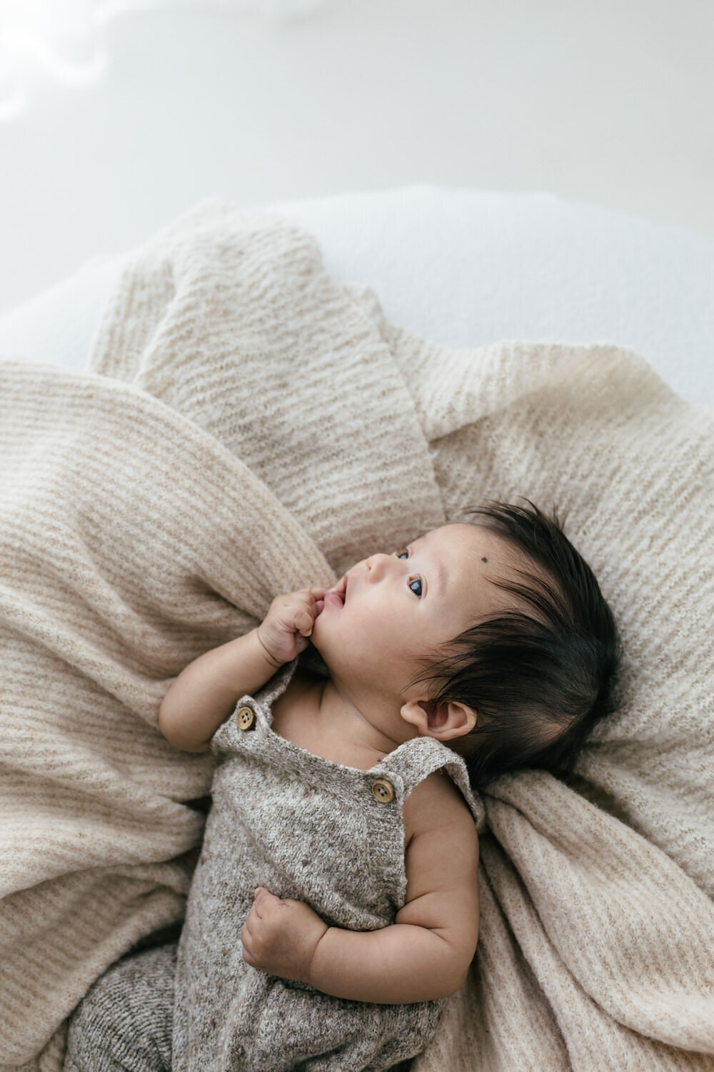 Baby awake and looking at the window whilst lying on a blanket