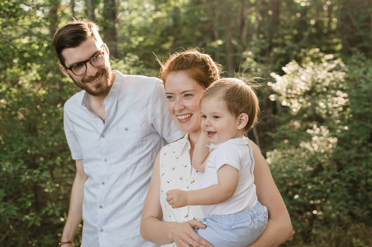 Couple walking through forest while carrying toddler.