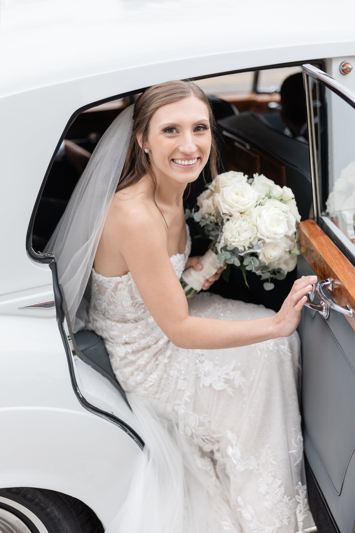 A bride steps out of a vintage Rolls Royce to go to her wedding