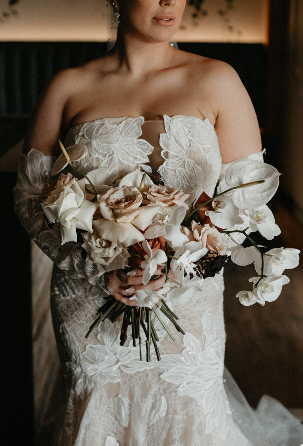 Bride posing with her lace wedding gown and elegant bouquet.