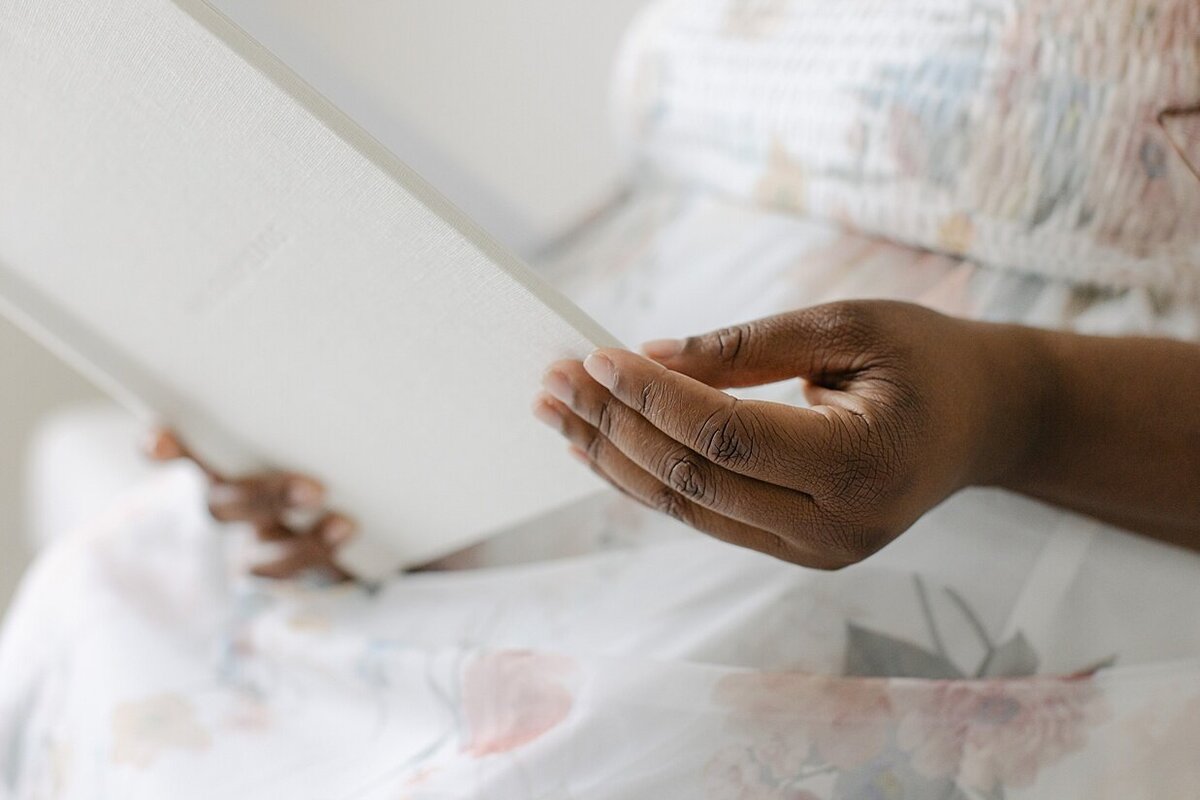 A close up of a woman in a floral dress holding an Indianapolis boudoir picture album.