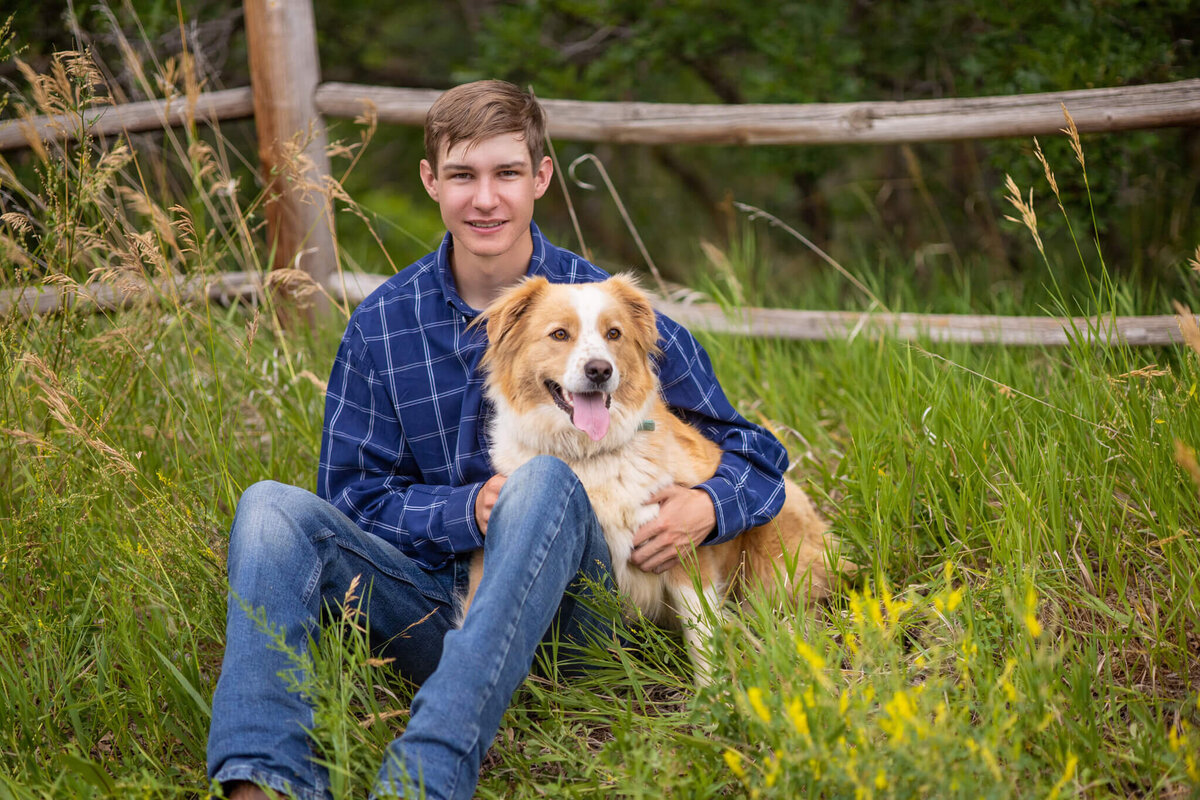 high school senior boy sitting in the grass with his dog