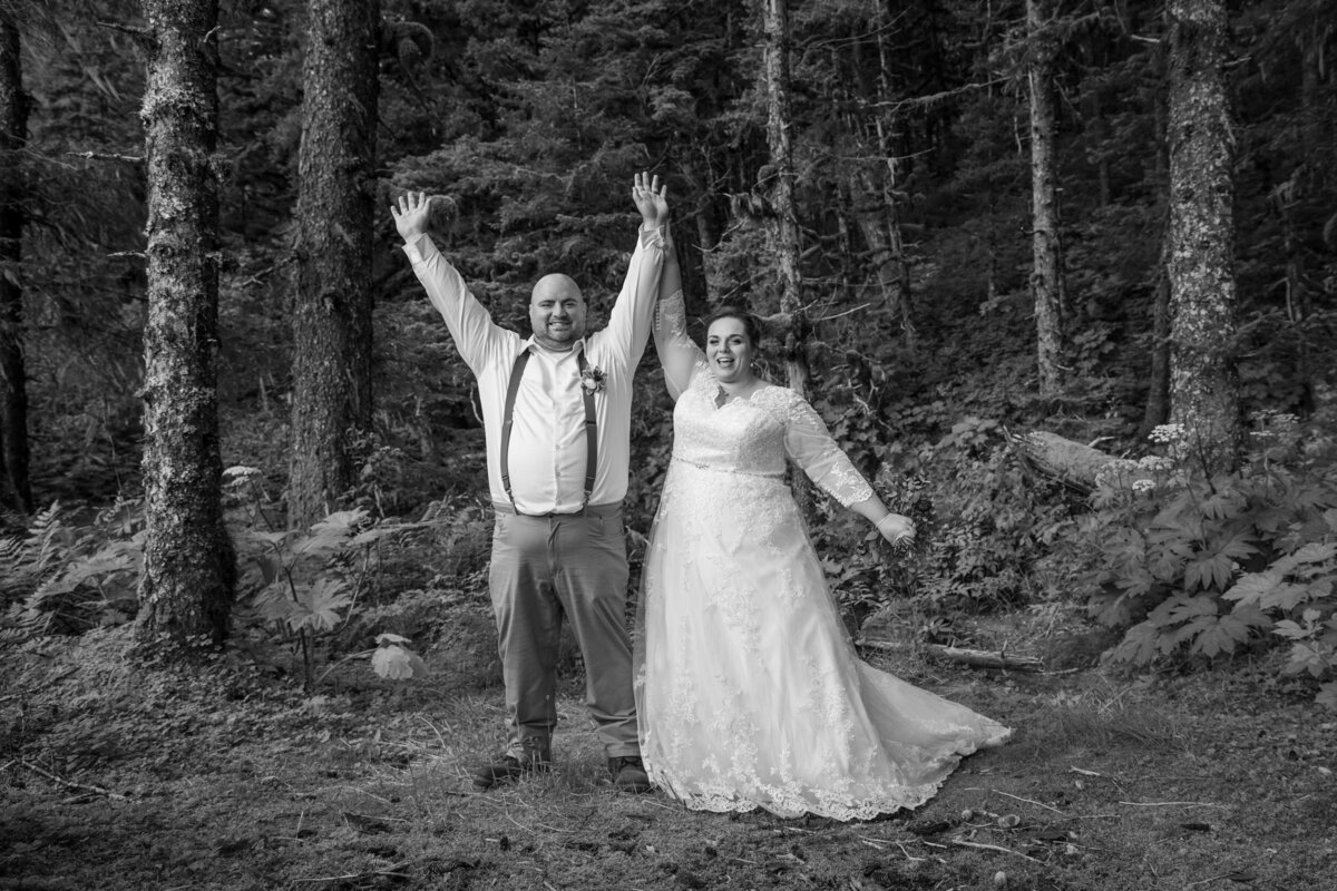 A bride and groom celebrate getting married with their hands in the air.