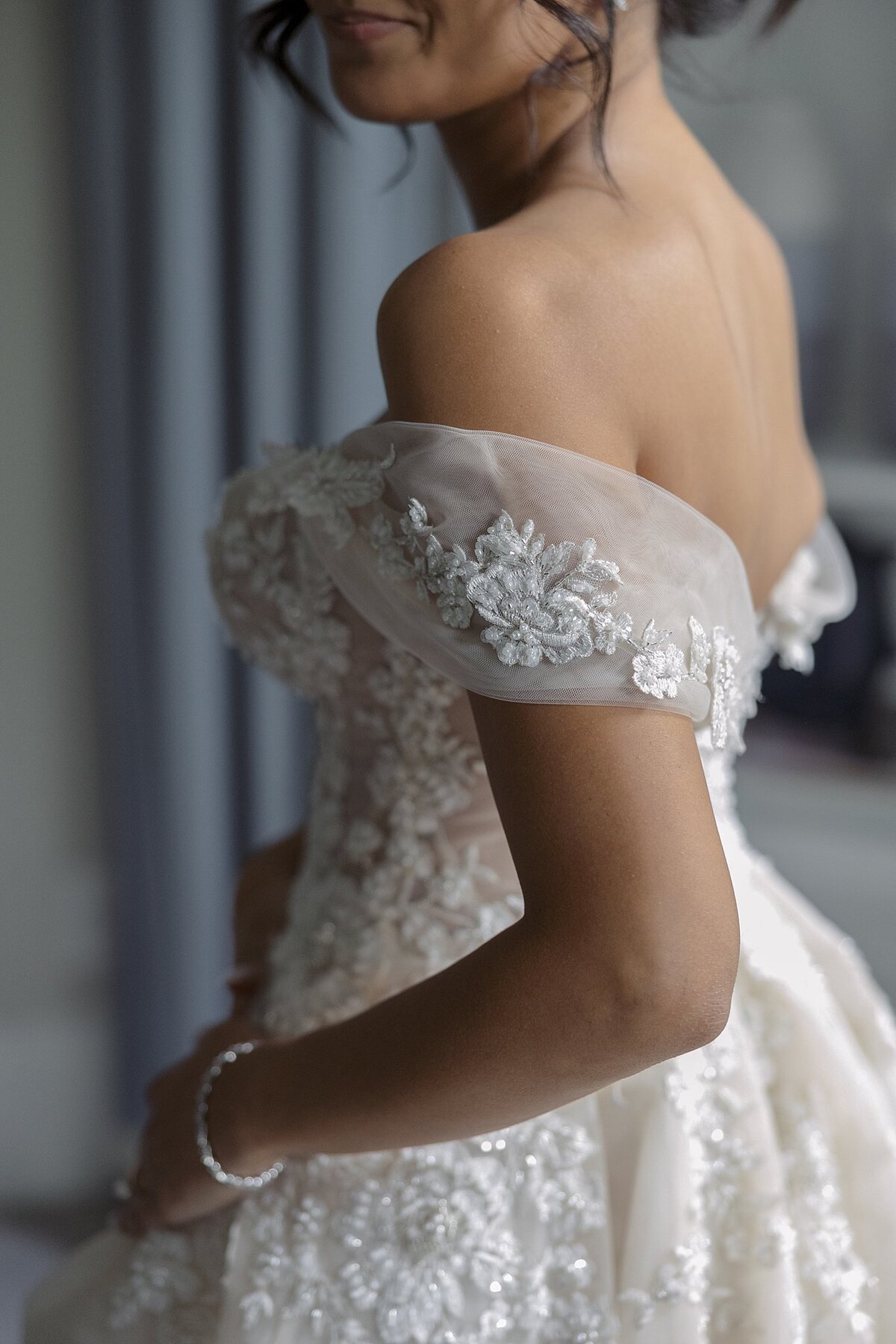 Bride wears an off the shoulder lace wedding dress. Deborah Zoe Photography