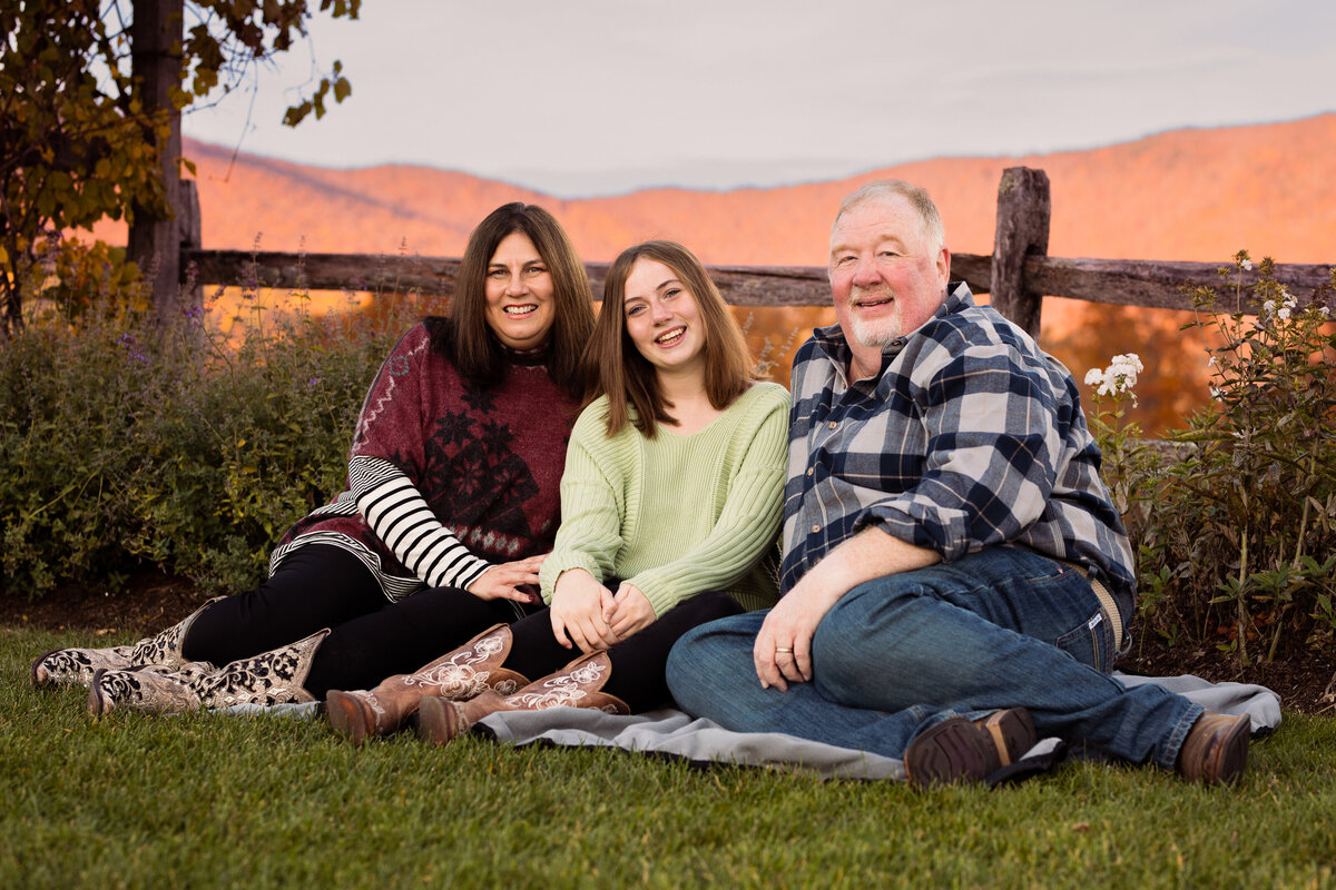 Mom, Dad, and teenaged daughter with fall foliage behind them by Vermont Family Photographer