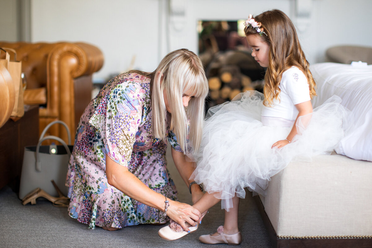 Bridesmaid helping flower girl put on her shoes
