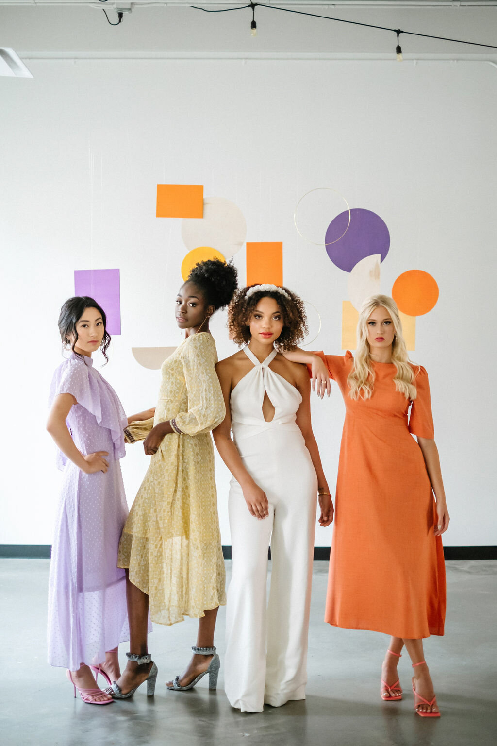Trendy bride in white pantsuit, and colourful bridesmaids dresses, with pops of orange, purple and yellow at The Brownstone, modern and elegant Calgary, Alberta wedding venue, featured on the Brontë Bride Vendor Guide.