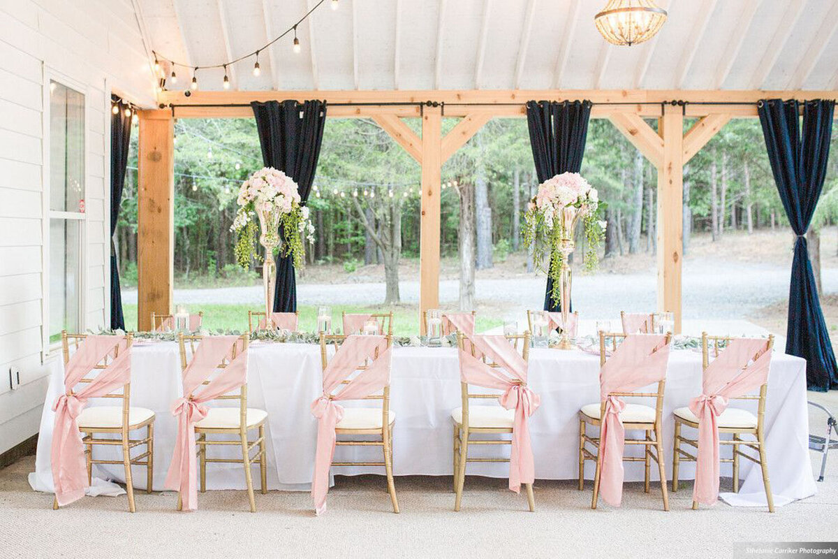 Outdoor reception table with pink chair sashes and floral centerpieces