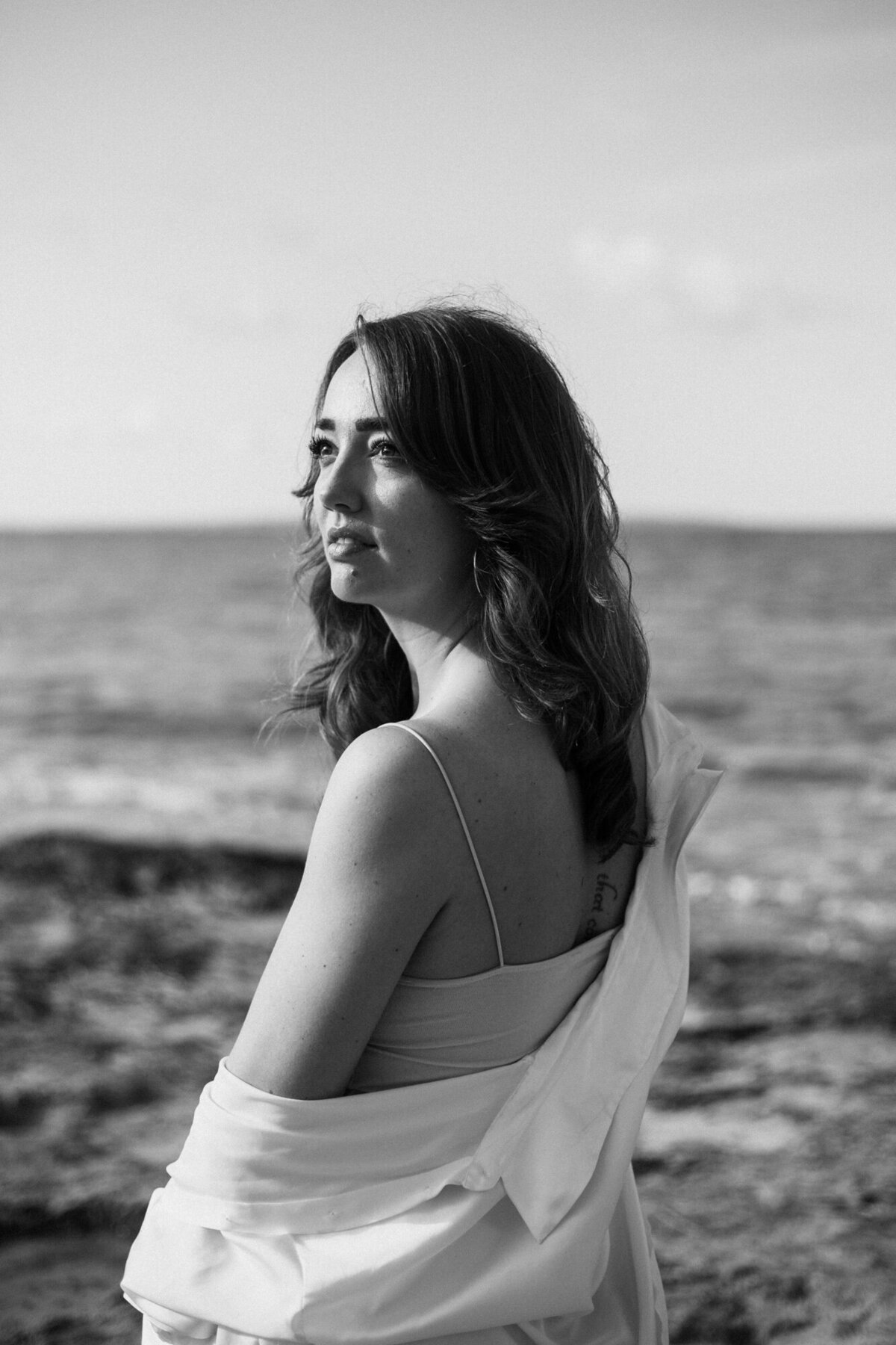 Woman is looking into the sun in front of the sea on ibiza for a photoshoot