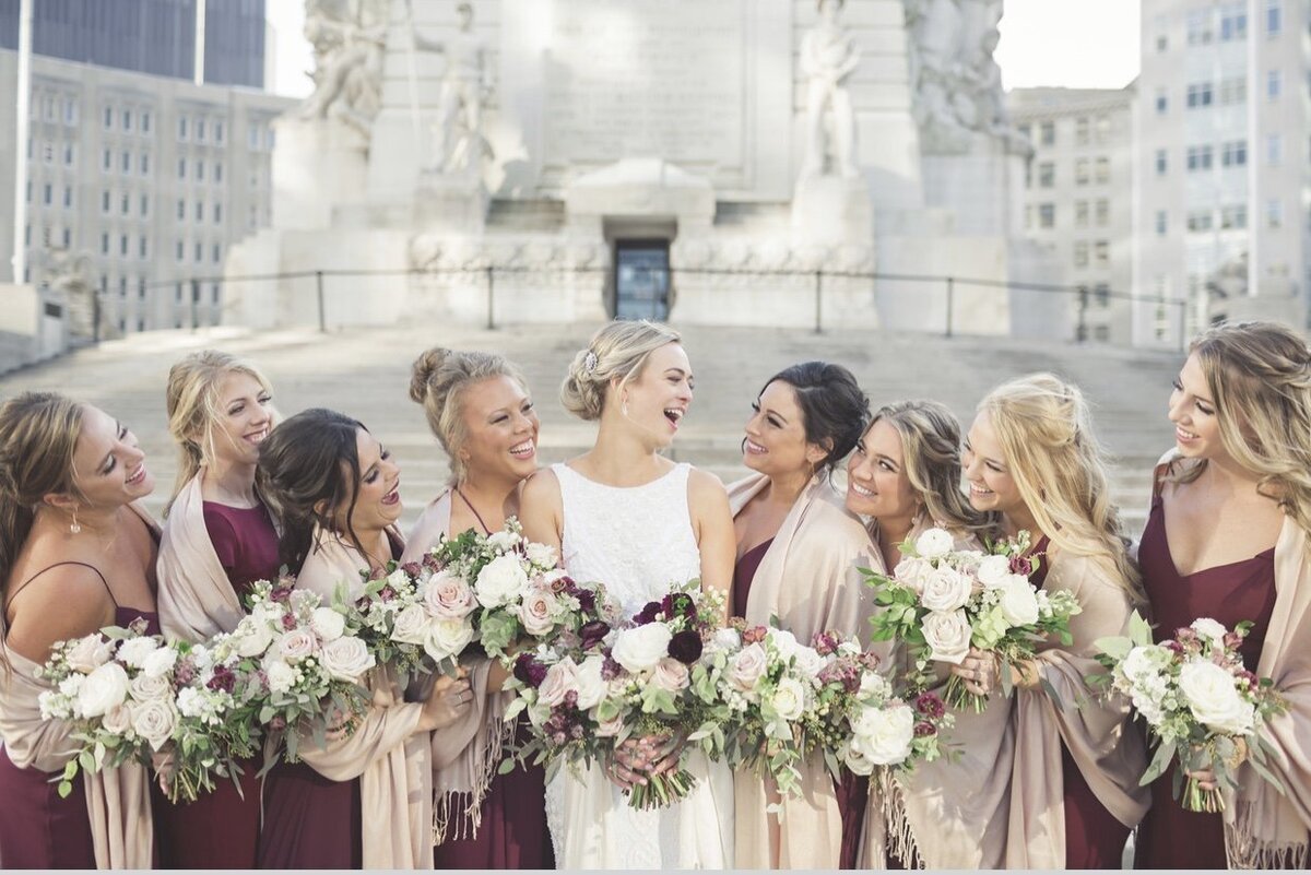 Bride and bridesmaids laughing with bouquets