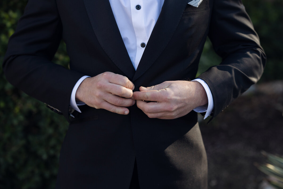 Closeup detail of groom hands and suit jacket