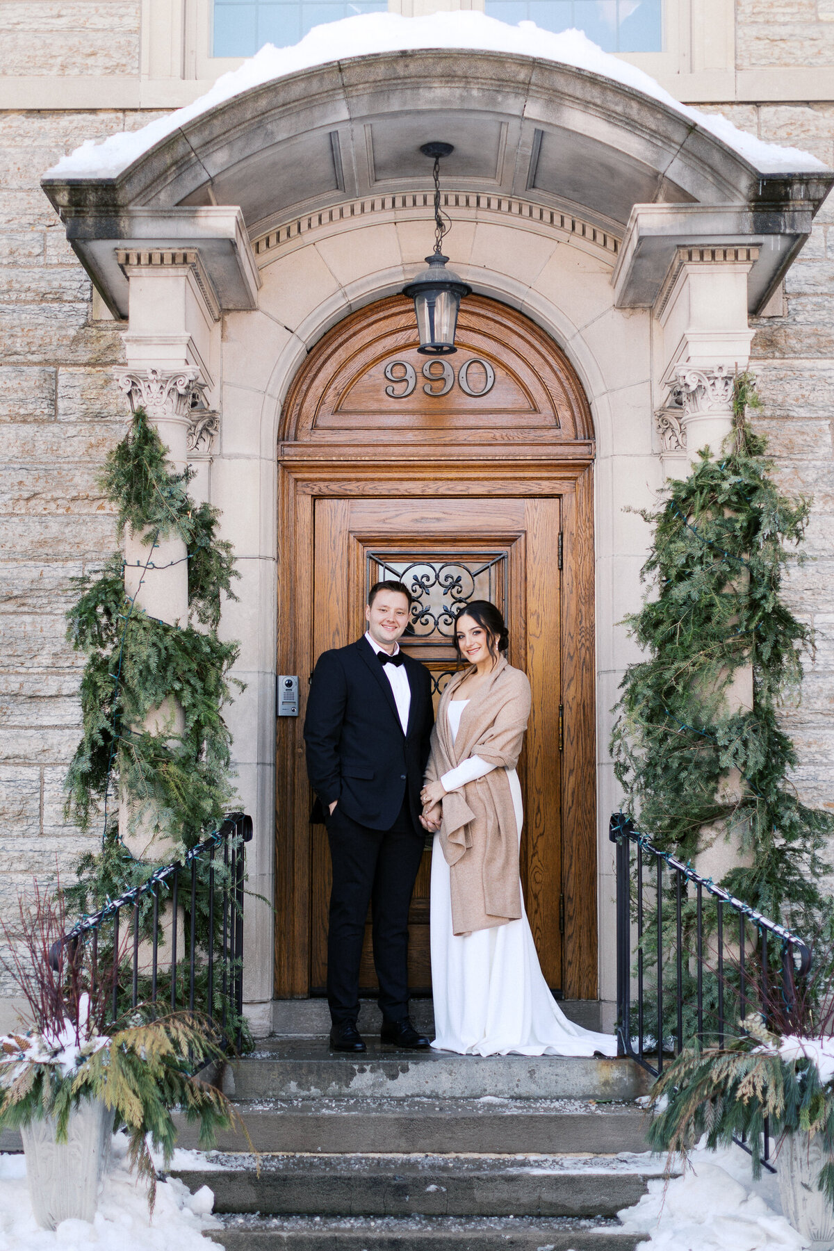 Bride and groom posing for a photo at the entrance door of St. Paul College Club
