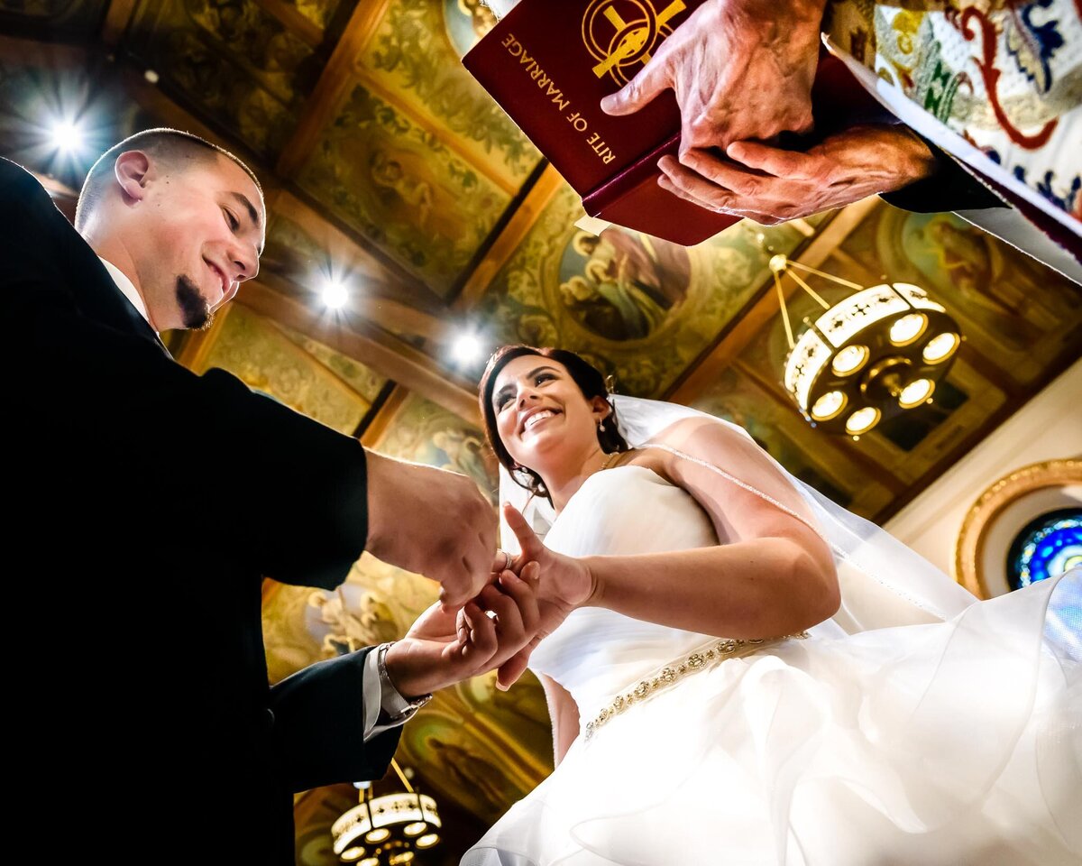 A groom slips the ring onto his bride's finger