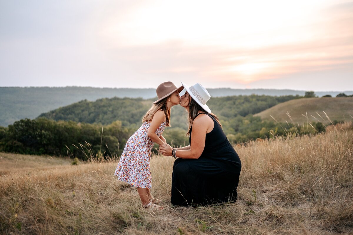 Mom and daughter touching noses on hilltop