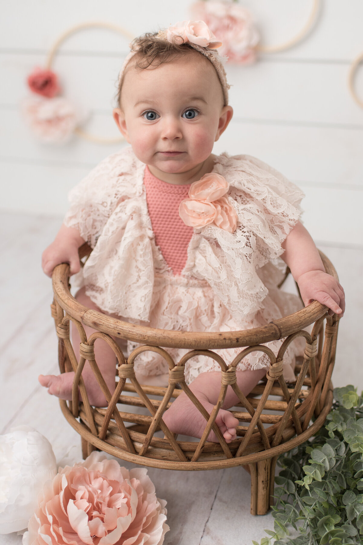 Baby girl sitting in basket, smiling at camera