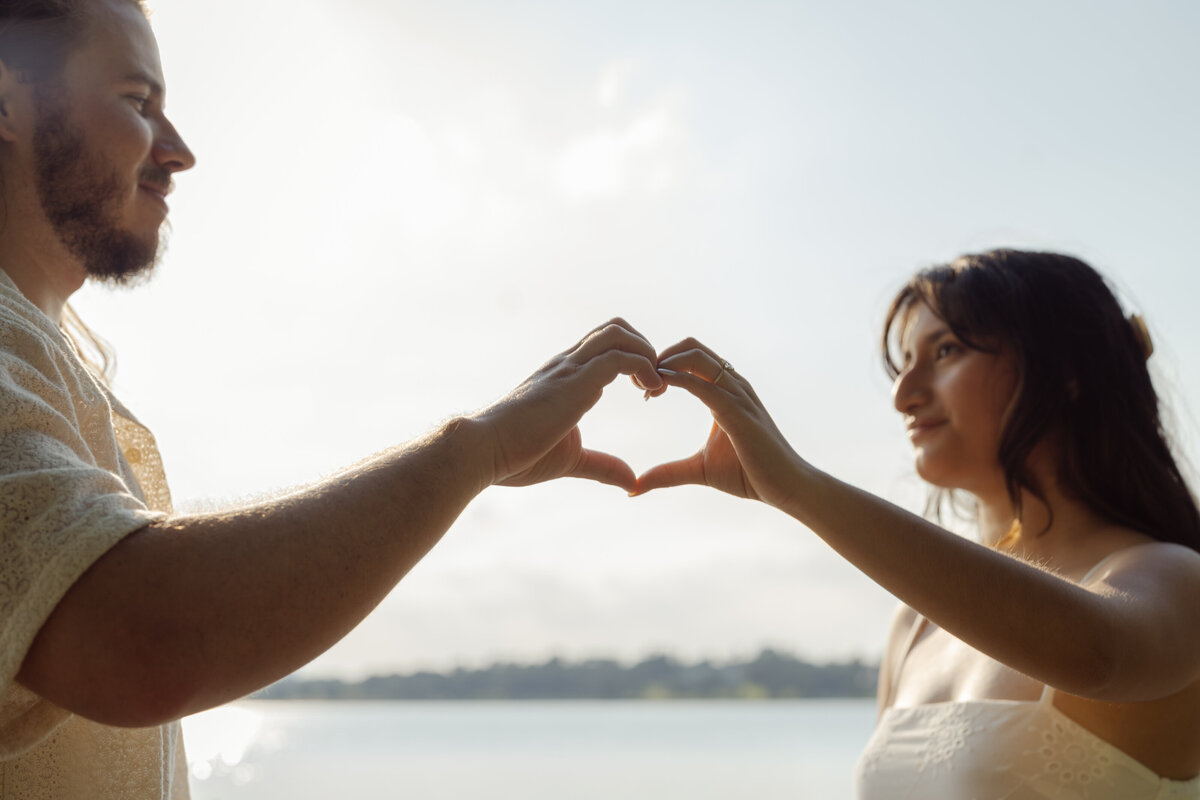 A playful moment where the couple creates a heart with their hands, taken during their engagement session at White Rock Lake.