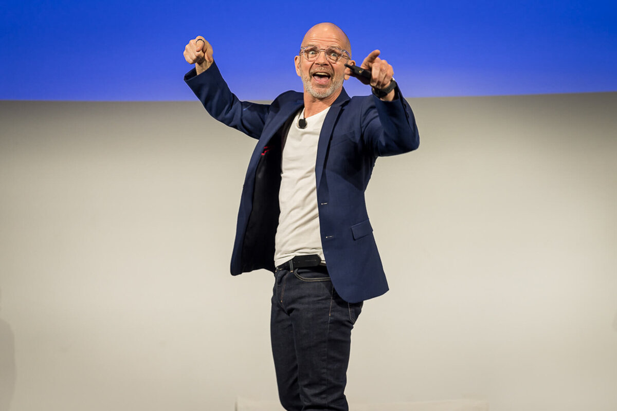 Professional headshot style of keynote speaker raising hands confidently while presenting during corporate conference new jersey.