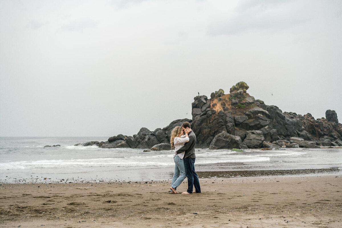 A couple embracing and kissing on the beach in Lincoln City. 