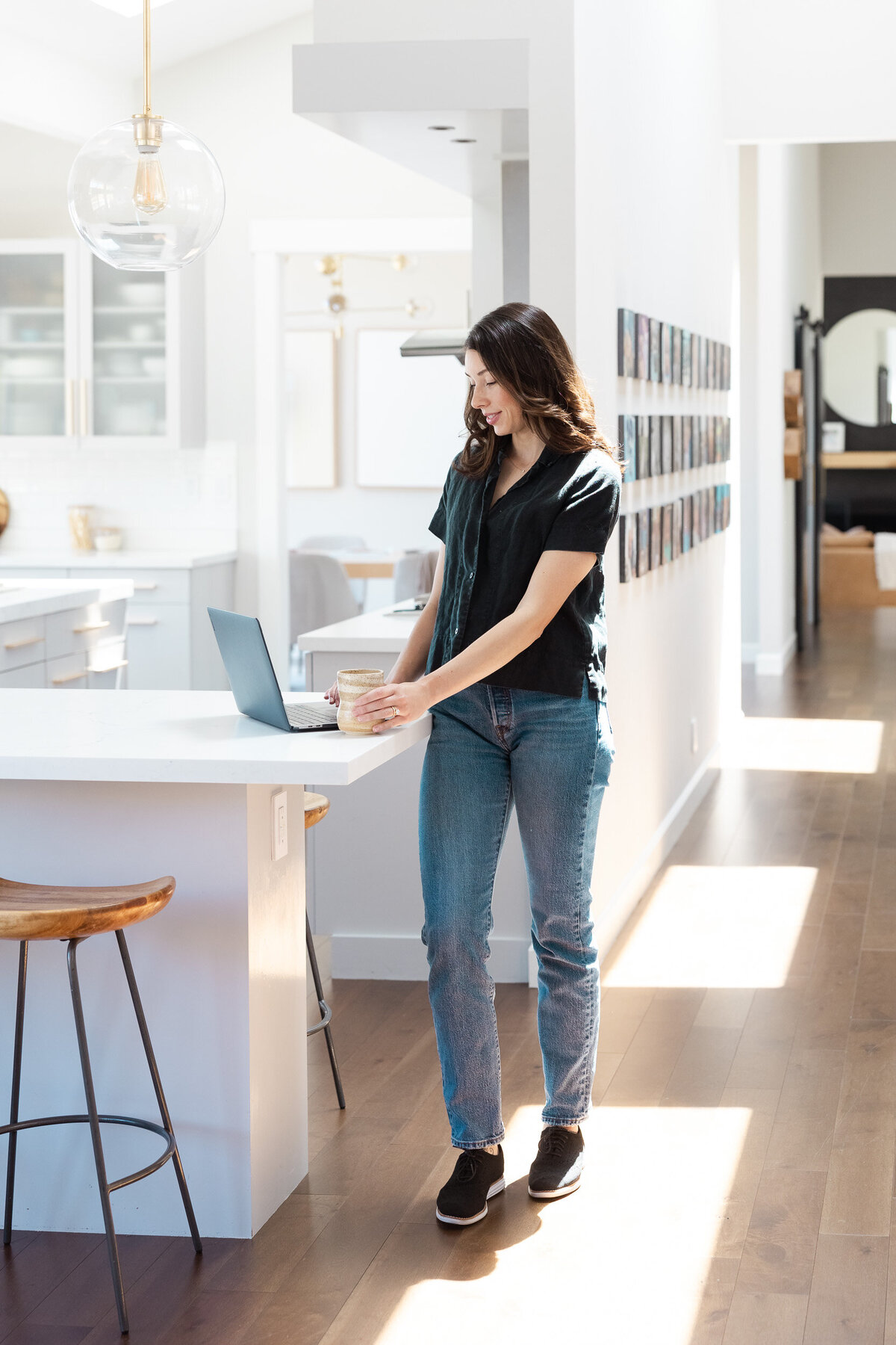 Interior Designer standing in kitchen working on her laptop