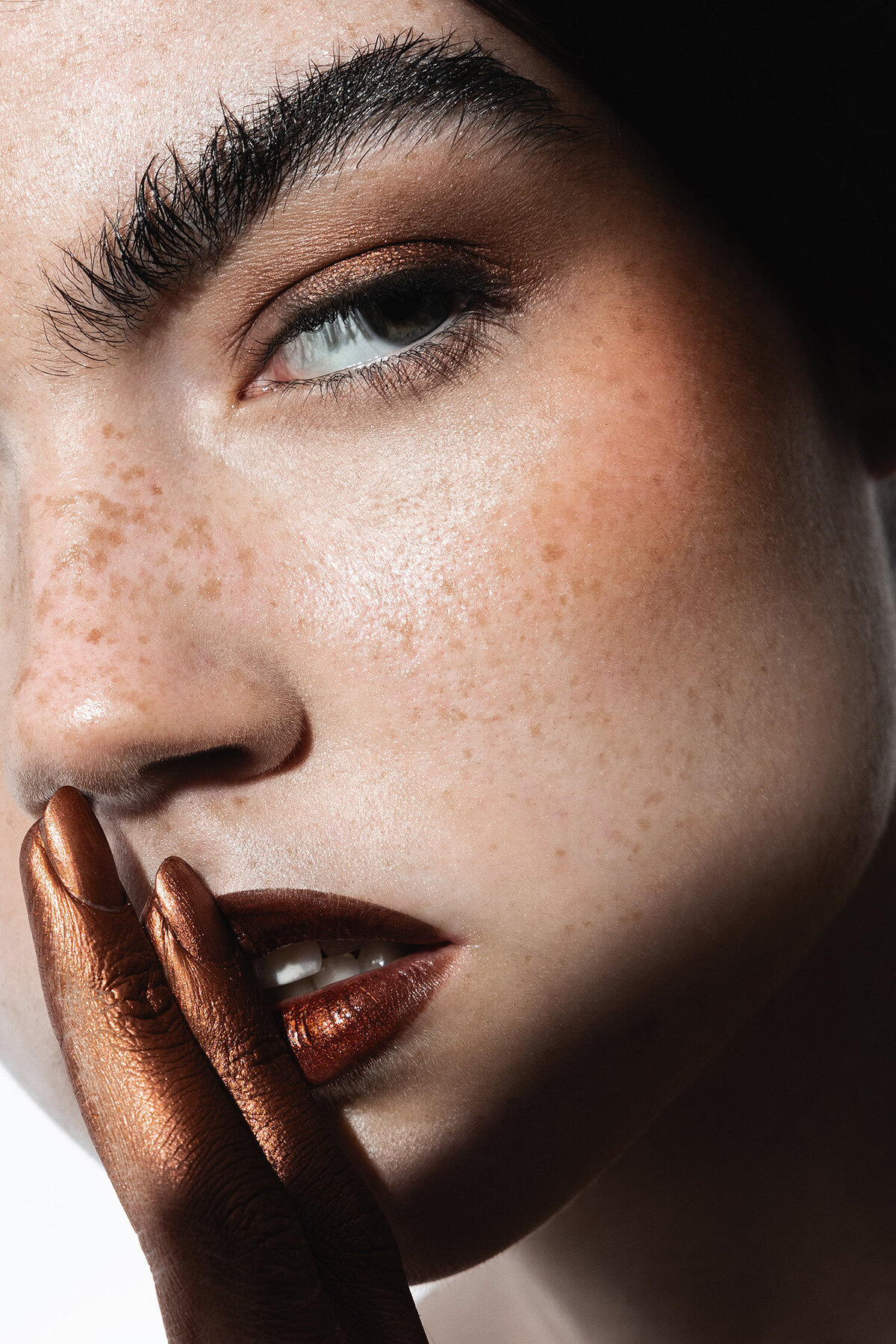 Dramatic beauty photography close-up of freckled model with metallic rust lips and eyeshadow