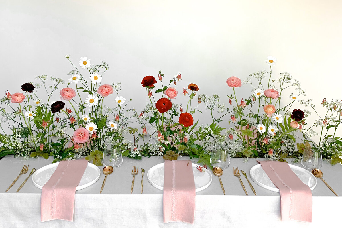 An airy garden centerpiece of bright spring flowers on a table at a Montreal wedding reception.