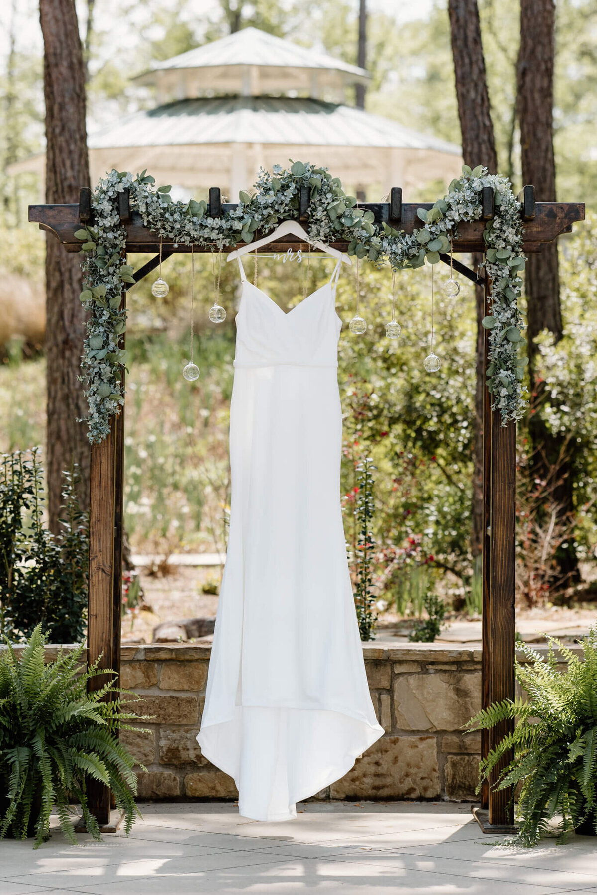 wedding dress hanging from decorated wooden arch at East Texas elopement venue