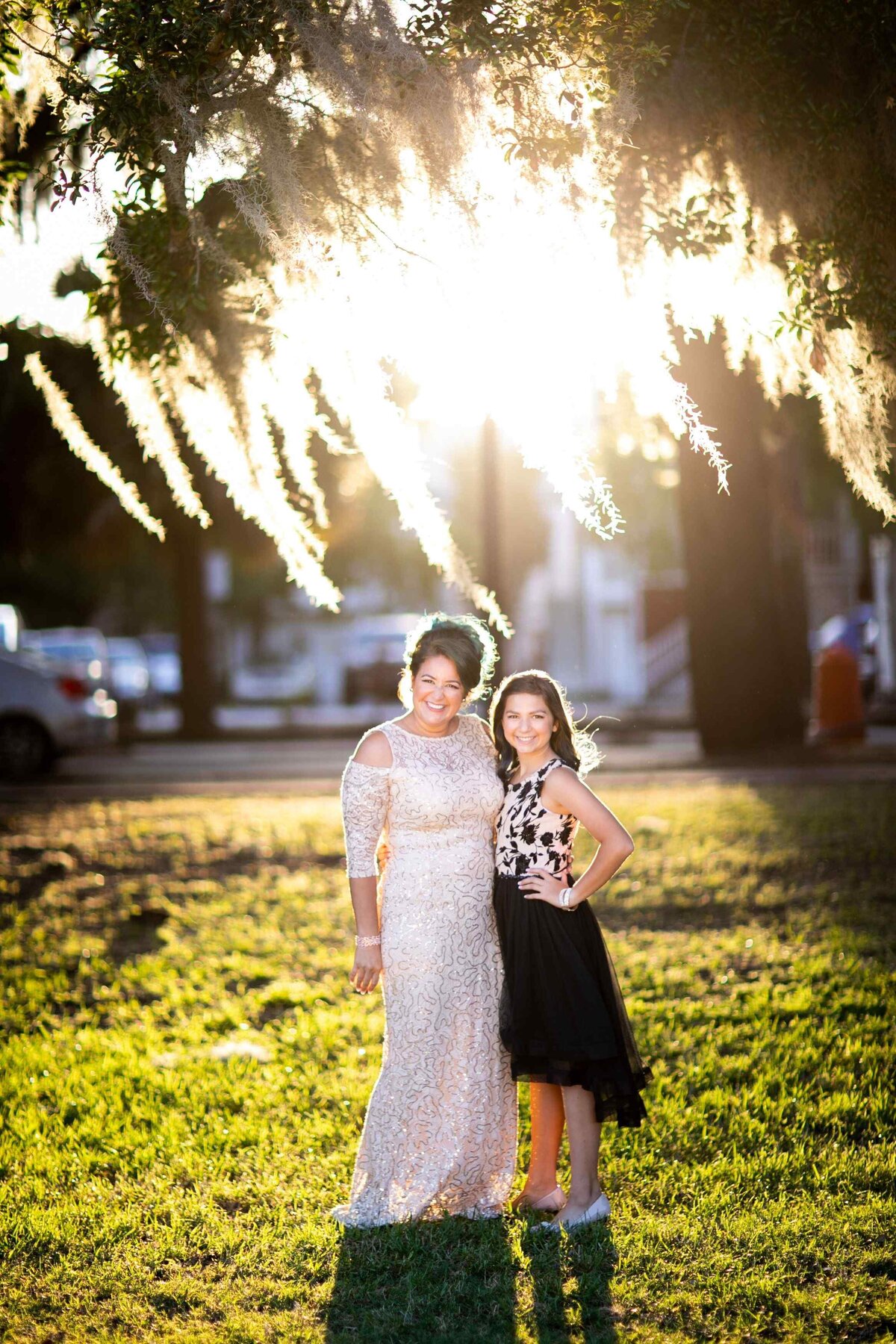 mother and daughter posed under tree