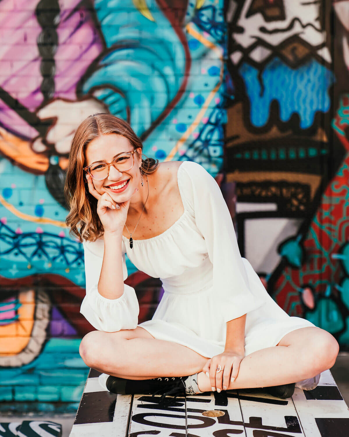 denver photographey senior pictures - teen girl smiling in white dress near wall art