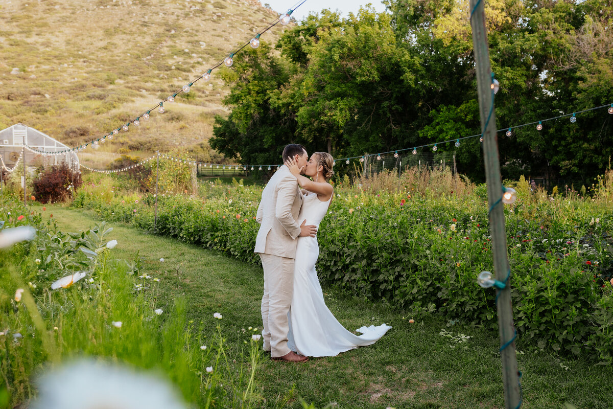 A bride and groom kiss eachother in the flower garden of Lyons, Farmette.