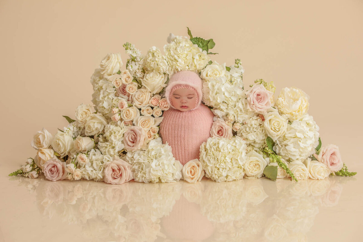Flowers around a baby girl wrapped in swadling cloth for a newbonr photoshoot