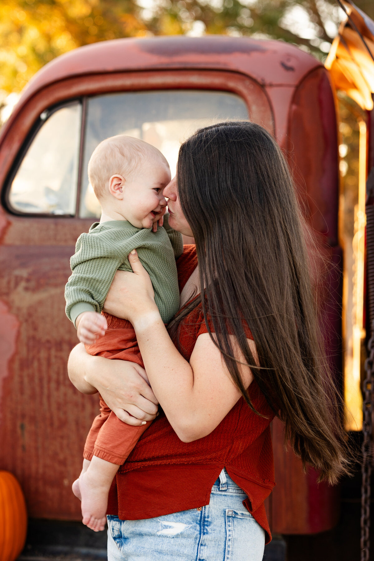 Mom holds baby boy and kisses him on the nose.