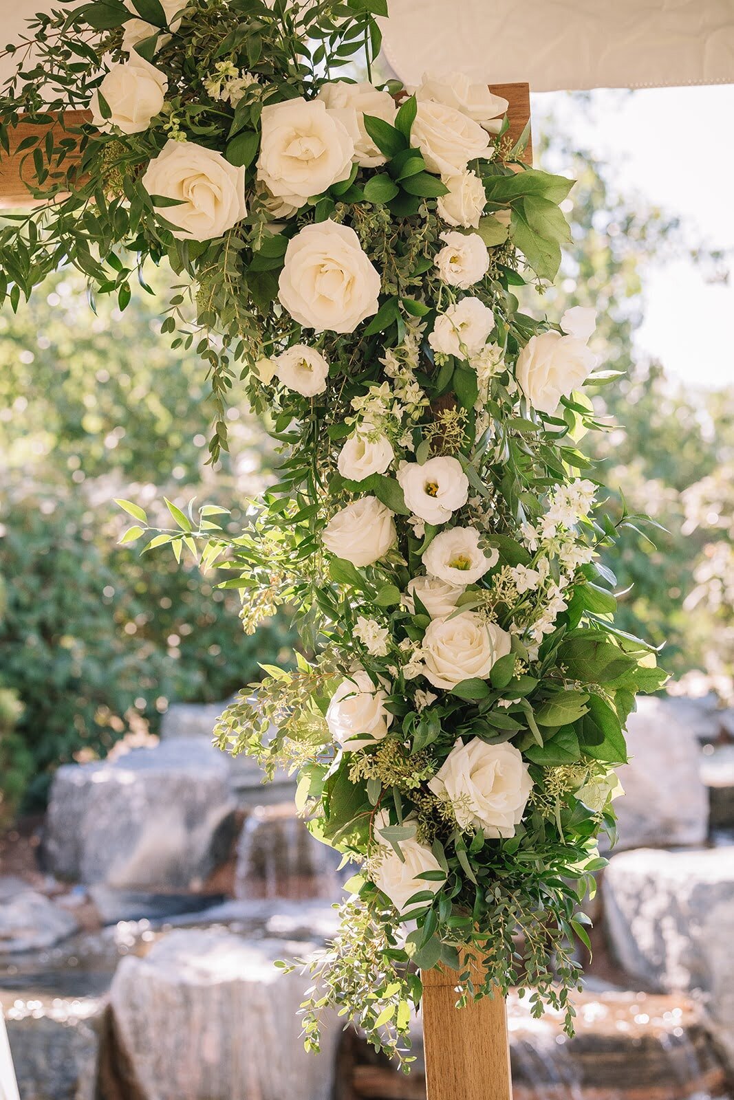 White flower and greenery corner arch  arrangement at a wedding ceremony.