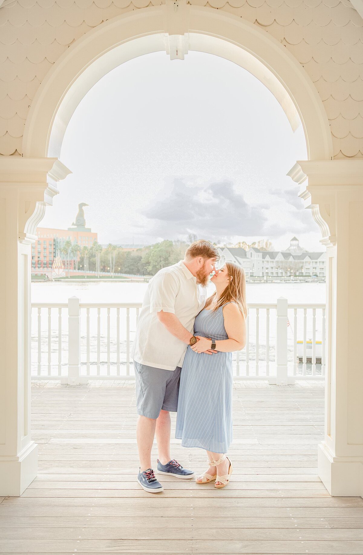 Couple kissing under beautiful arch  at  Disney's Boardwalk resort, in love during their honeymoon..