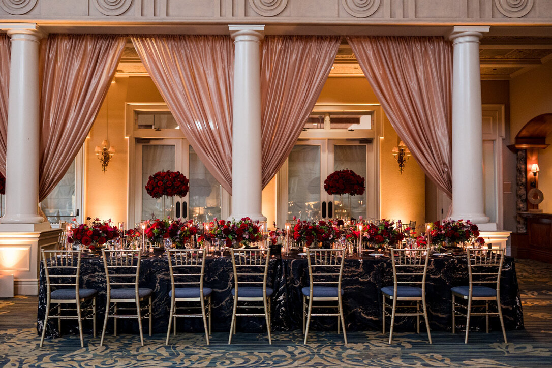 oblong arrangements, candle light, gold footed dishes, tea lights, black and white linens, gold rimmed glassware, black matte flatware, gold chairs, tall arrangements, kings tables, champagne drapery