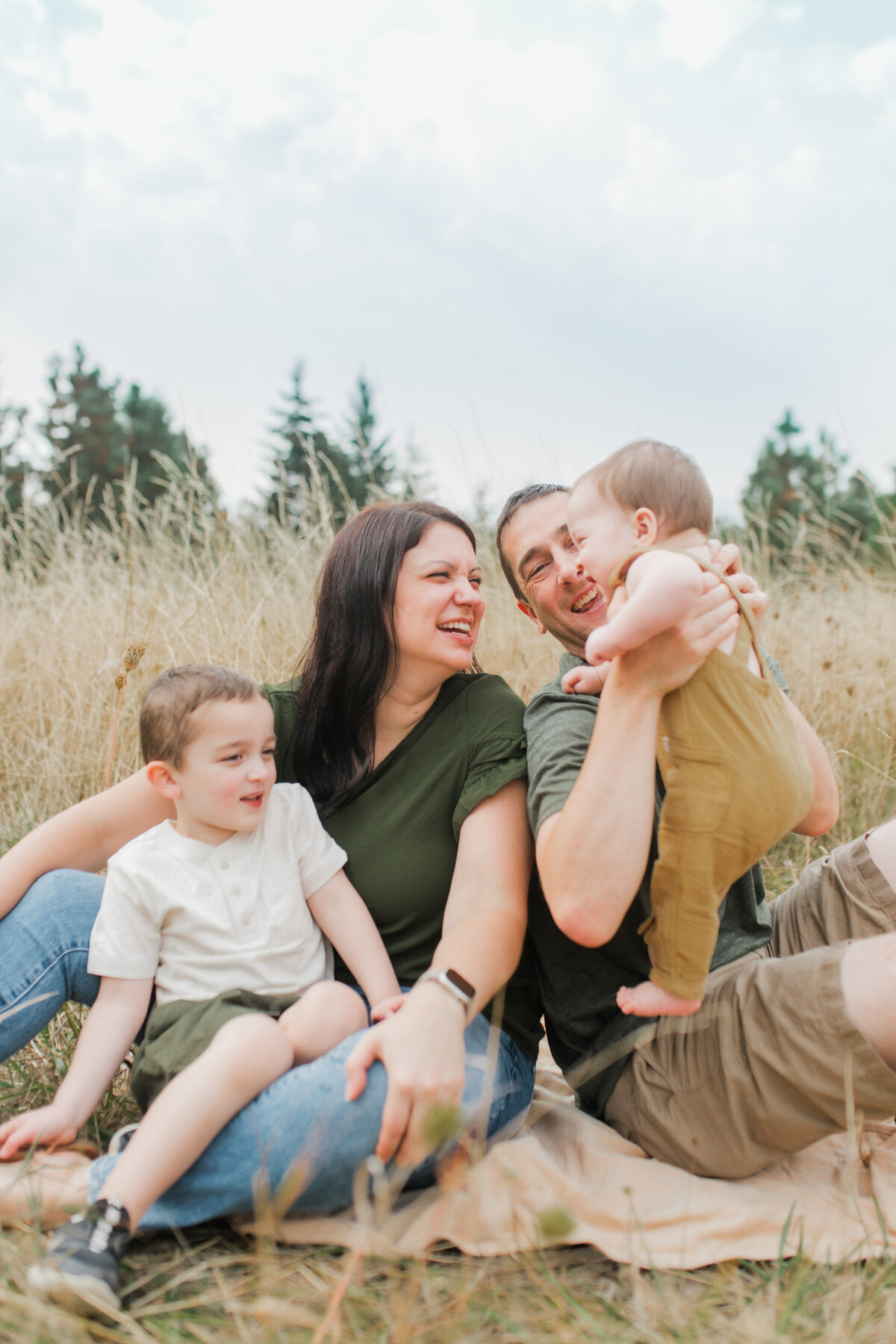 Family with two children sitting in a field, laughing together