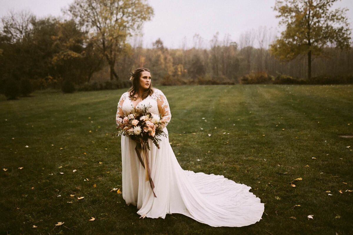 megan lang wedding - bride in field holding flowers