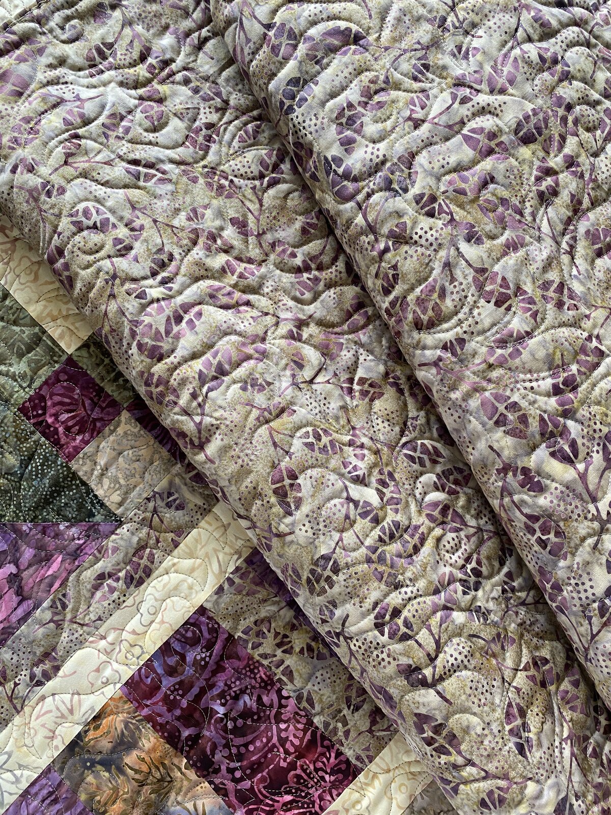 Whimsical rose quilting design featured on a purple floral quilt back.