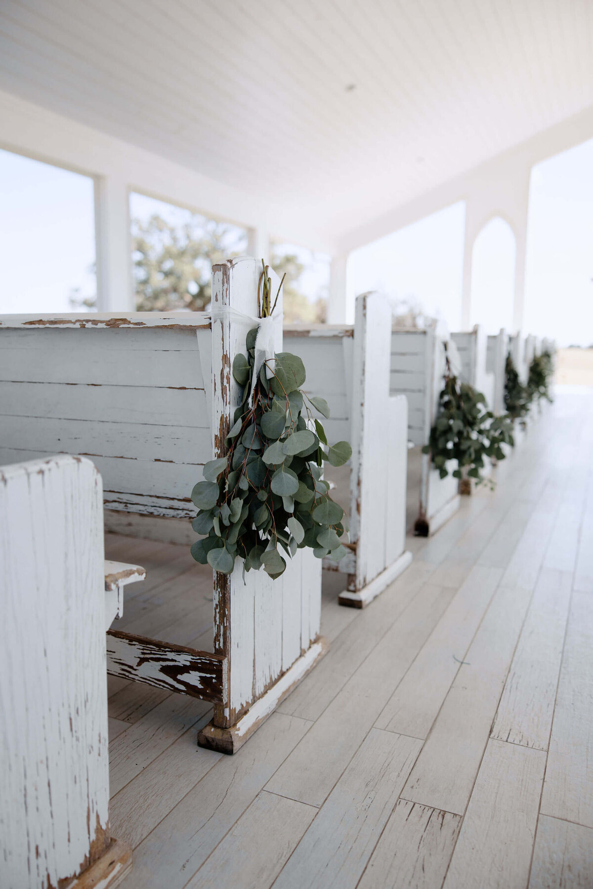 wedding chapel benches decorates with fresh eucalyptus