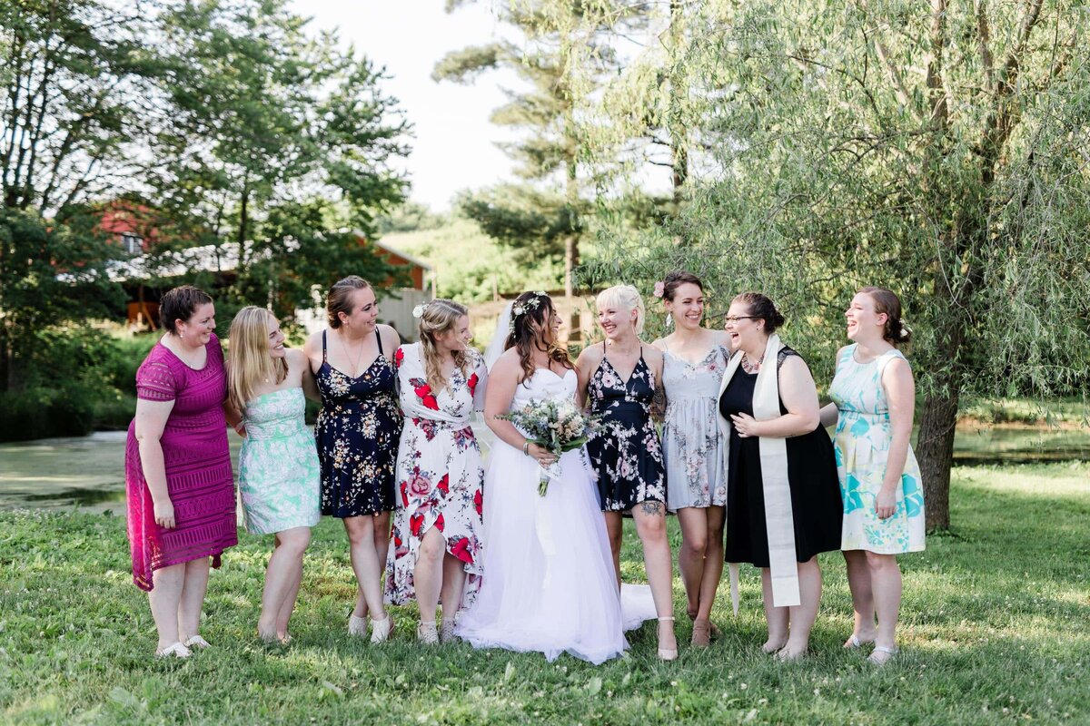 Bride and bridesmaids all wearing different dresses on a farm wedding