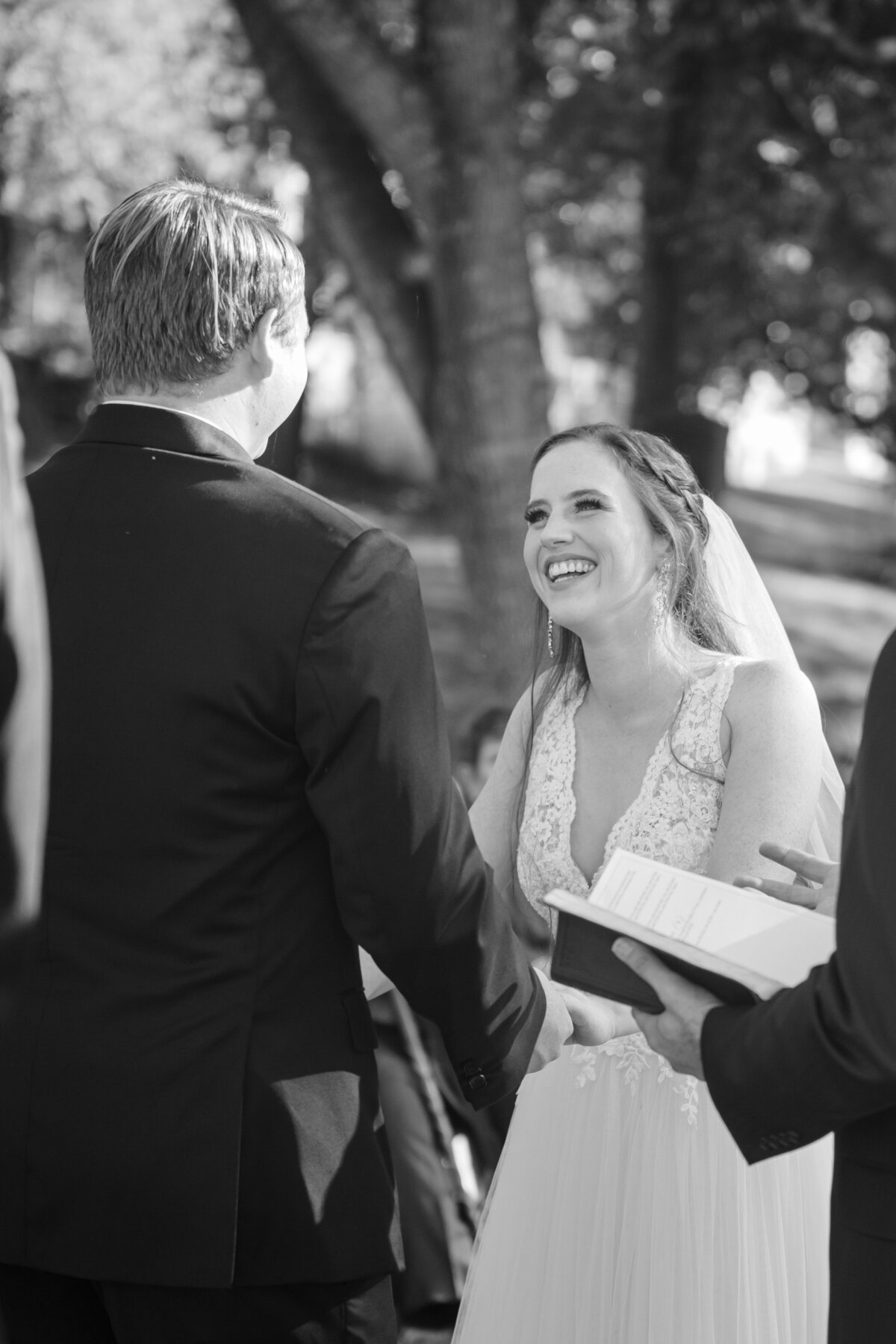 bride laughs with groom during ceremony black and white at Milltown Historic District New Braunfels